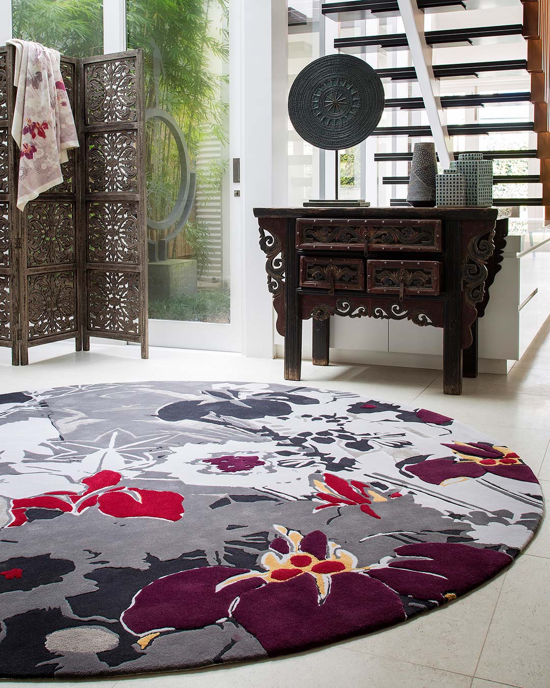 location bedroom shot of ayame round rug by akira floral pattern in grey purple and red